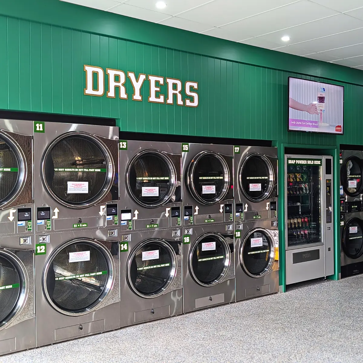 The wall of stacked dryers, with the vending machine that sells soap powder